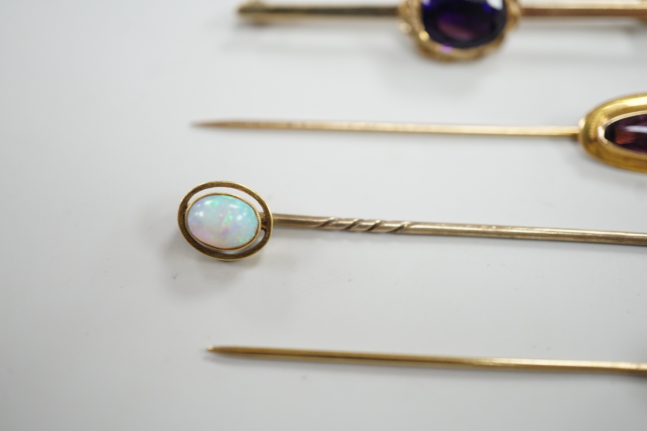 Three assorted yellow metal and gem set stick pins, including 9ct gold and diamond set horseshoe, 58mm and a modern 9ct gold and gem set bar brooch, gross weight 9.2 grams.